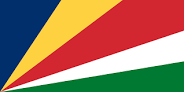 A flag with two yellow triangles at the top and bottom and two green triangles at the hoist and fly. These are surrounded by a red border charged with six five-pointed yellow stars – three at the top centre and three at the bottom centre – along with an additional star on a red disc at the centre and a nutmeg at the hoist triangle