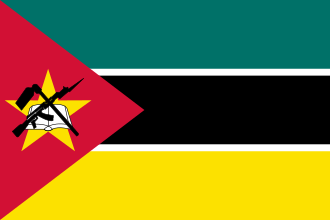 A flag with two yellow triangles at the top and bottom and two green triangles at the hoist and fly. These are surrounded by a red border charged with six five-pointed yellow stars – three at the top centre and three at the bottom centre – along with an additional star on a red disc at the centre and a nutmeg at the hoist triangle